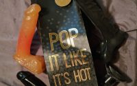 a bag reading "pop it like its hot" surrounded by dildo and buttplugs